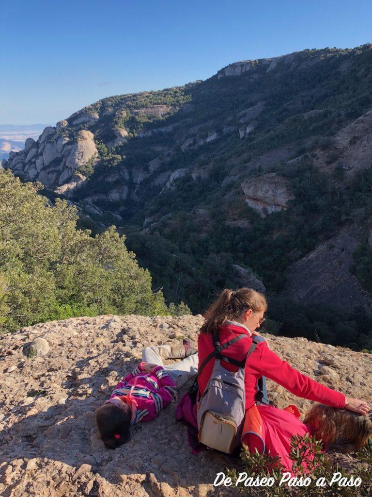 Madre e hija descansando sobre una roca, con vistas desde lo alto de las montañas Montserrat