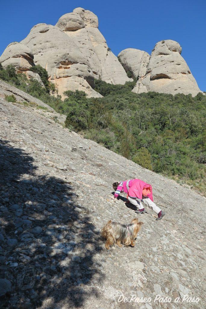 Niña y perra escalando rocas