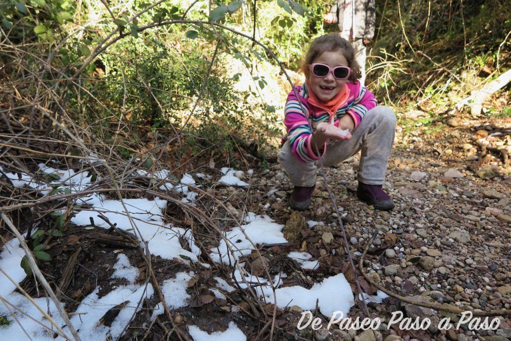 Niña jugando nieve en el sueldo del bosque