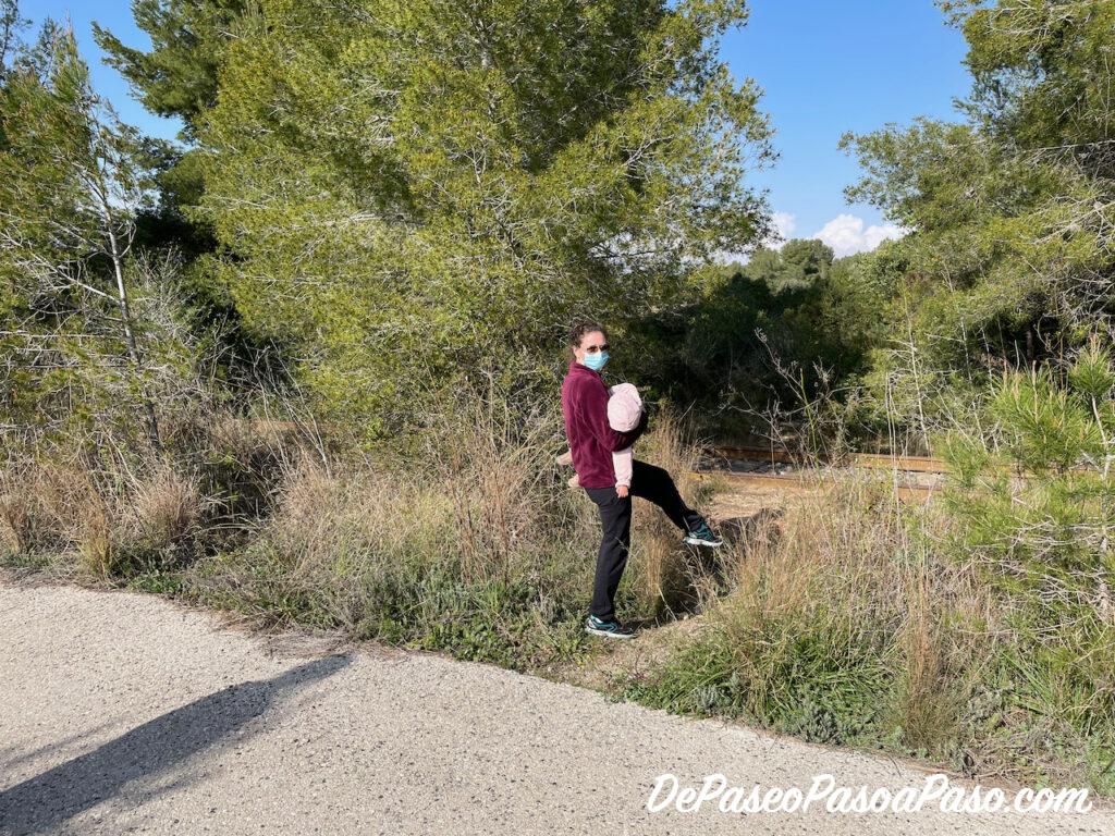 mujer buscando el paso sin vegetación para llegar a la vía de tren abandonada