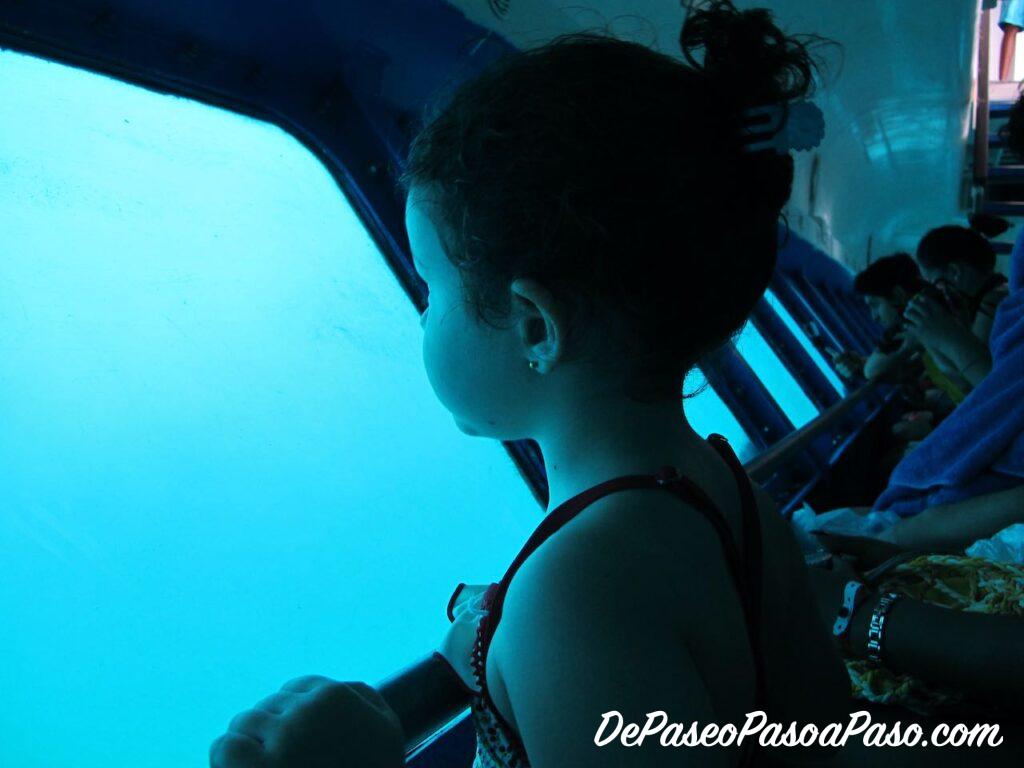 Niña observando el mar en un barco con suelo de cristal